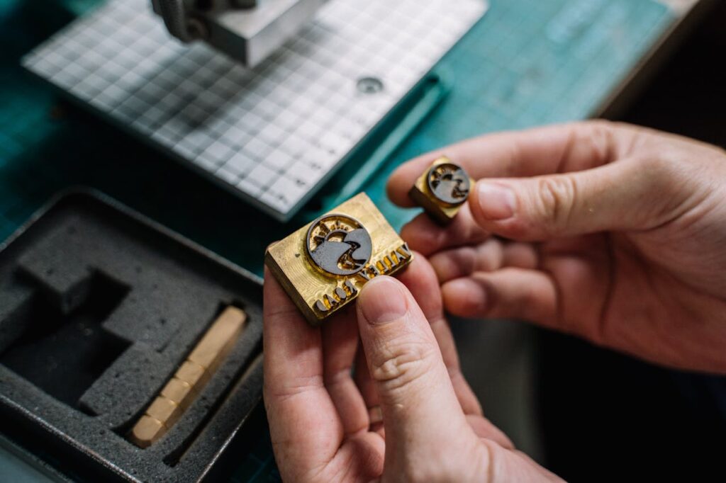 pexels photo 5963063 Close-up view of hands holding handcrafted brass stamps on a workbench.