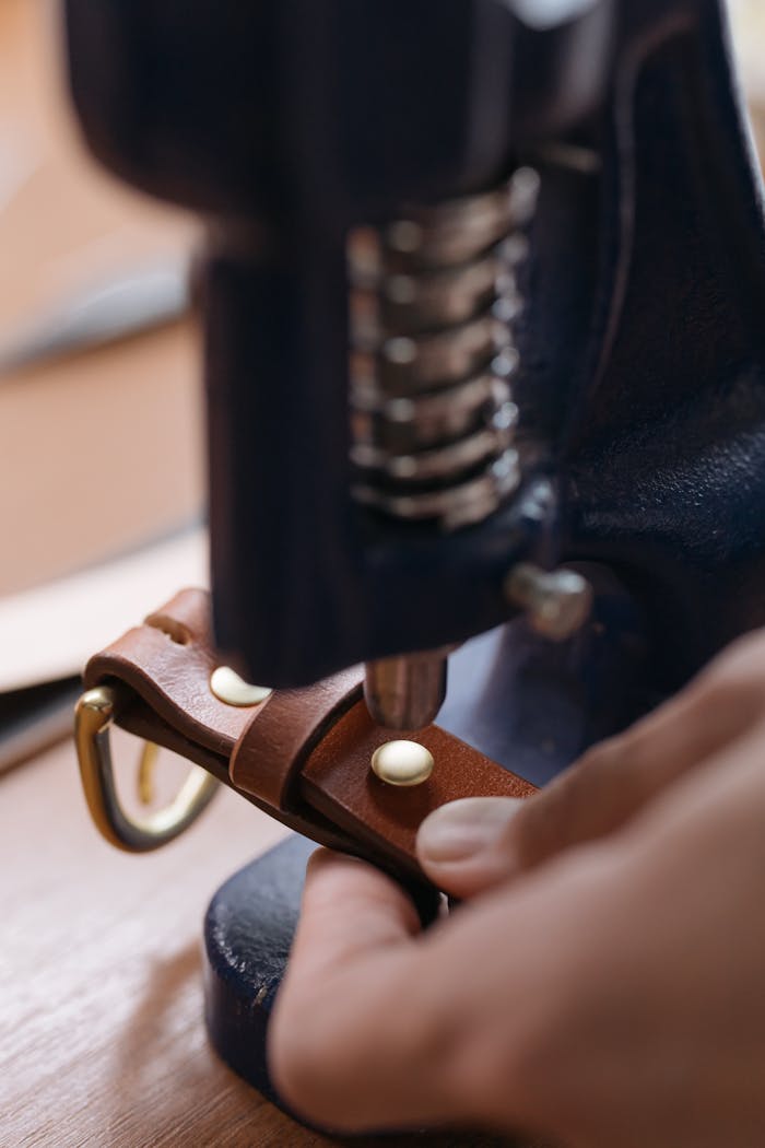 about-img Detailed view of crafting a leather belt using a press machine, showcasing craftsmanship.