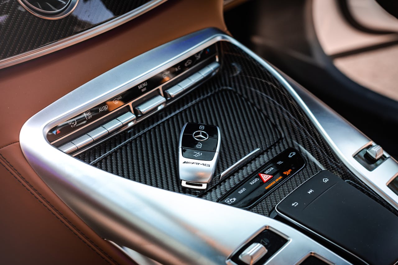 service-01 Close-up view of a luxury car's control panel featuring carbon fiber and chrome details with a key fob.