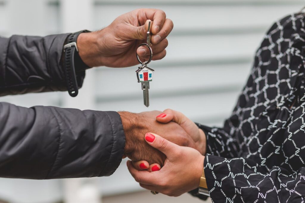 pexels photo 8293778 Close-up of a realtor handing over a house key to a new homeowner, symbolizing ownership and investment.